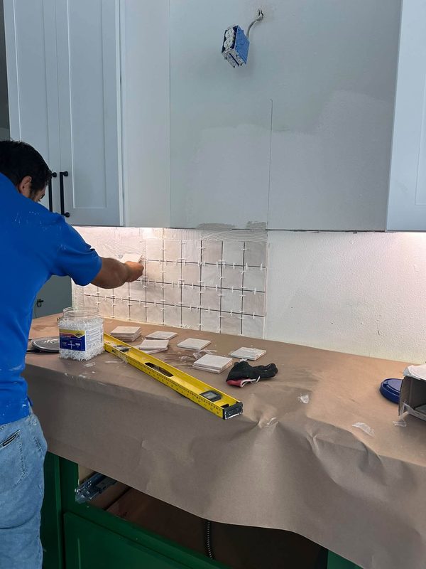 Setting a tile backsplash above new green base cabinets