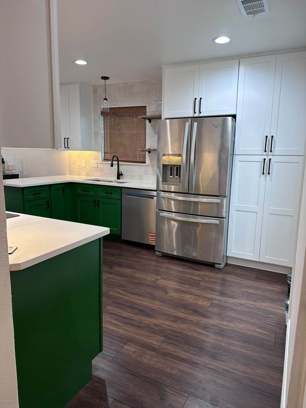 Green cabinet kitchen with stainless refrigerator and plank floor