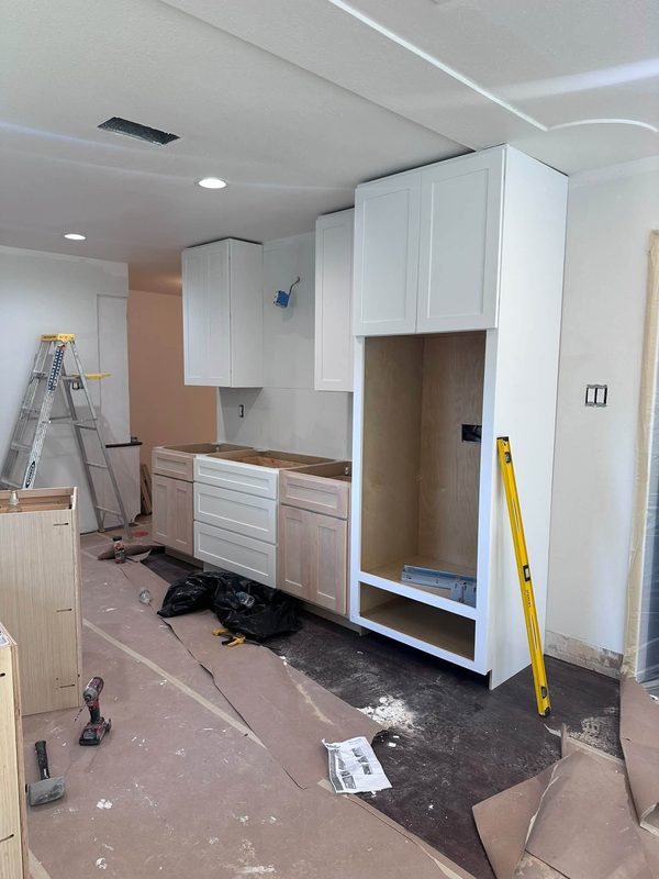 White upper cabinets hung before the counters and backsplash