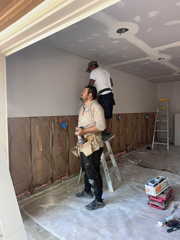 Crew hanging drywall over new insulation