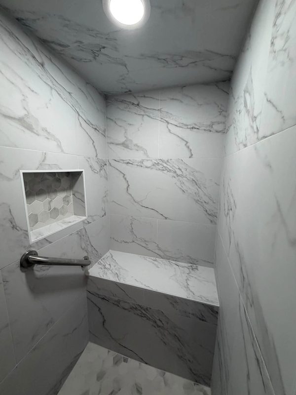Finished walk in shower with bench, niche and hex tile floor