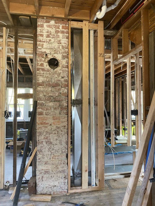 Framing taken back to studs around an exposed brick chimney
